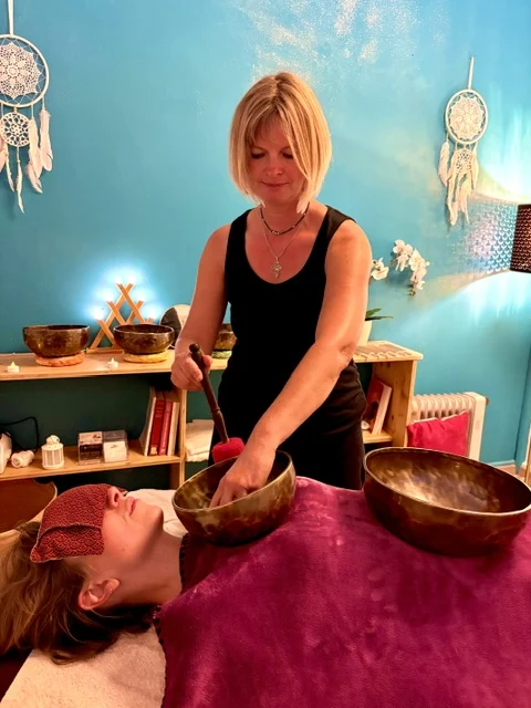 Lydia faisant vibrer un bol tibétain pendant un soin sonore sur table